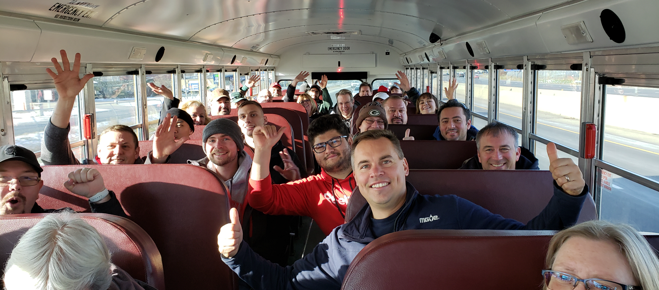 People smiling and waving from their seats during one of our real estate bus tours